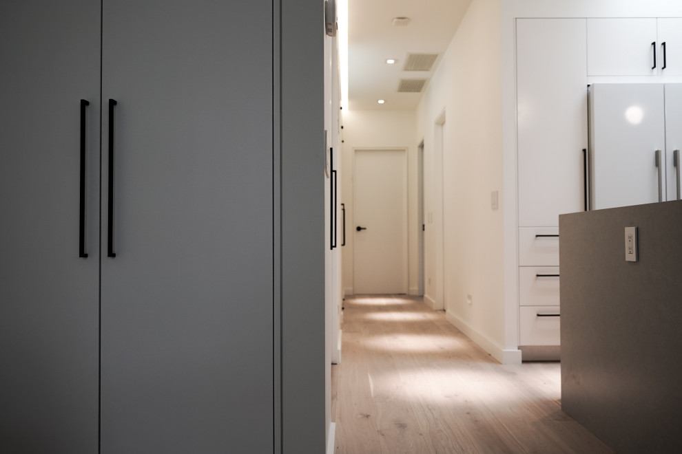 Inspiration pour un couloir design de taille moyenne avec un mur blanc, parquet clair et un sol marron.
