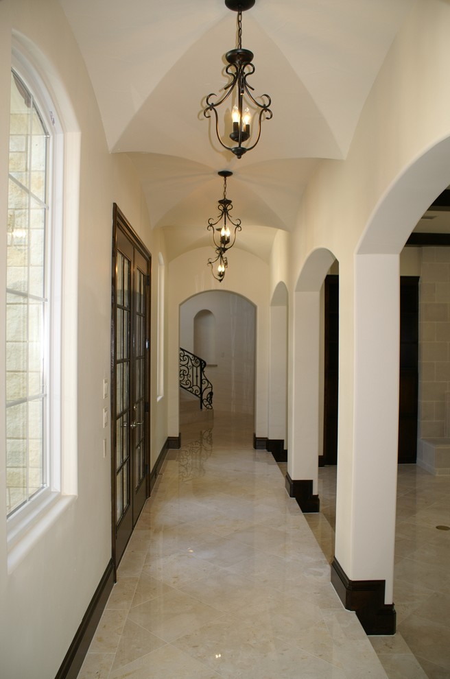 Hallway - large mediterranean limestone floor hallway idea in Dallas with beige walls