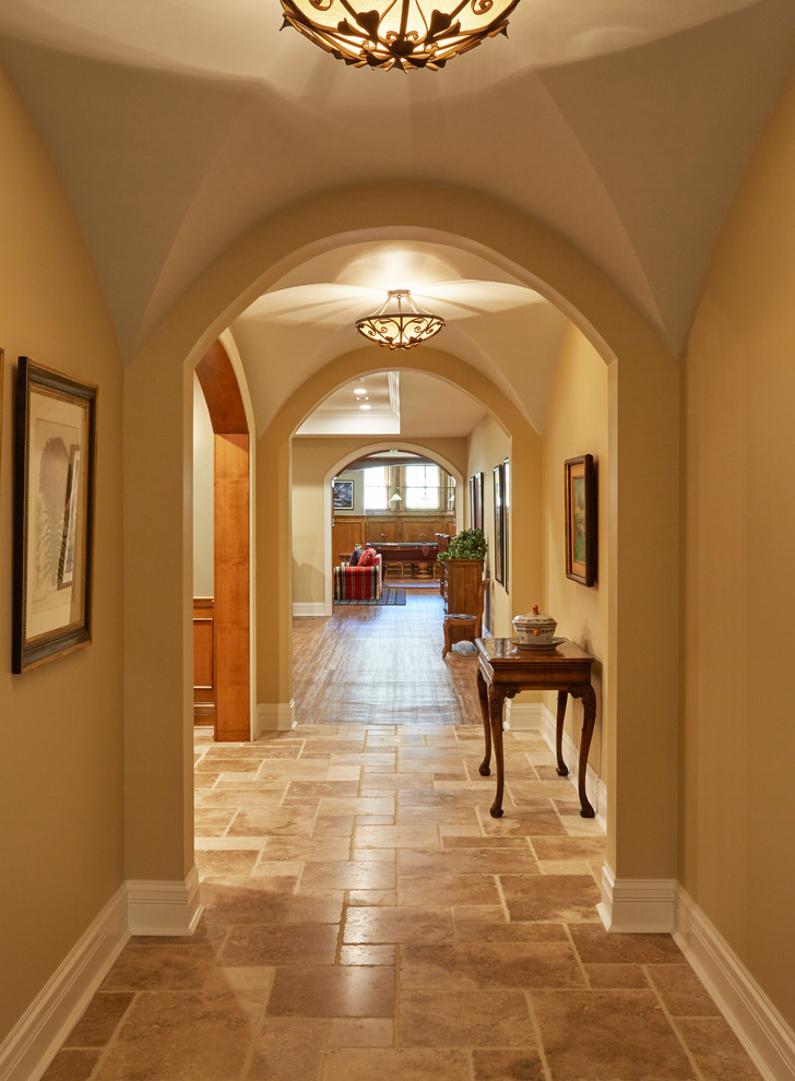 Exempel på en stor klassisk hall, med orange väggar, kalkstensgolv och brunt golv
