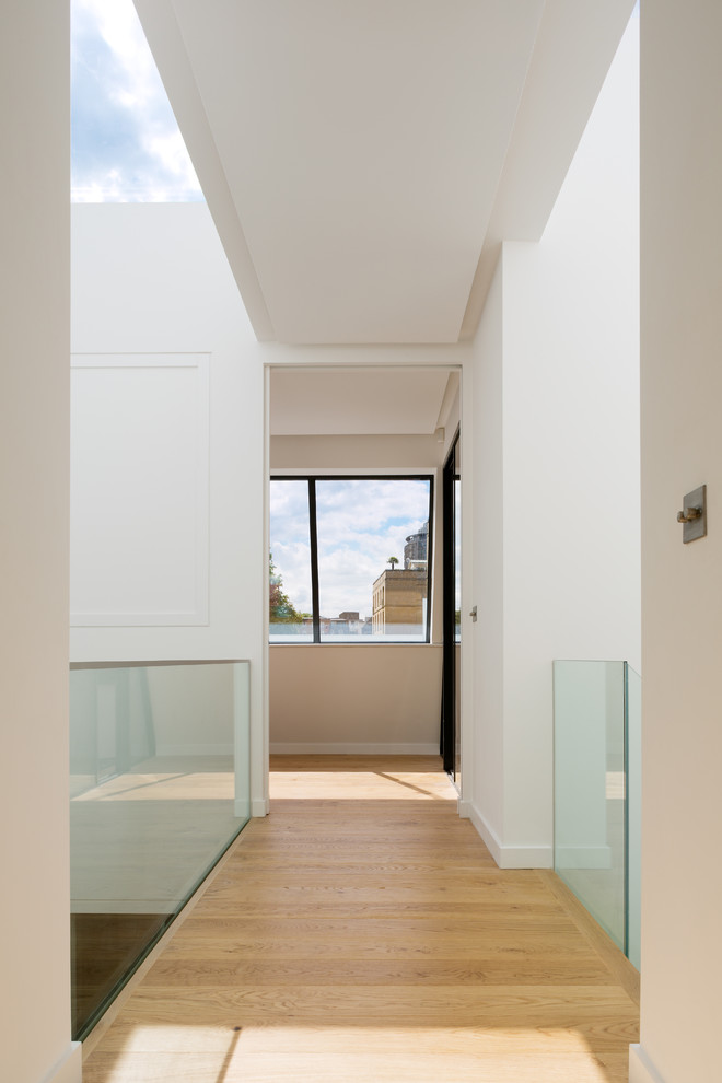 Foto de recibidores y pasillos contemporáneos de tamaño medio con paredes blancas, suelo de madera en tonos medios y suelo marrón