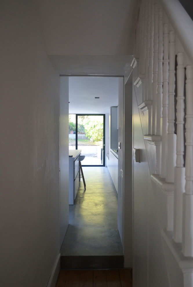 Ispirazione per un grande ingresso o corridoio chic con pareti bianche e pavimento in cemento