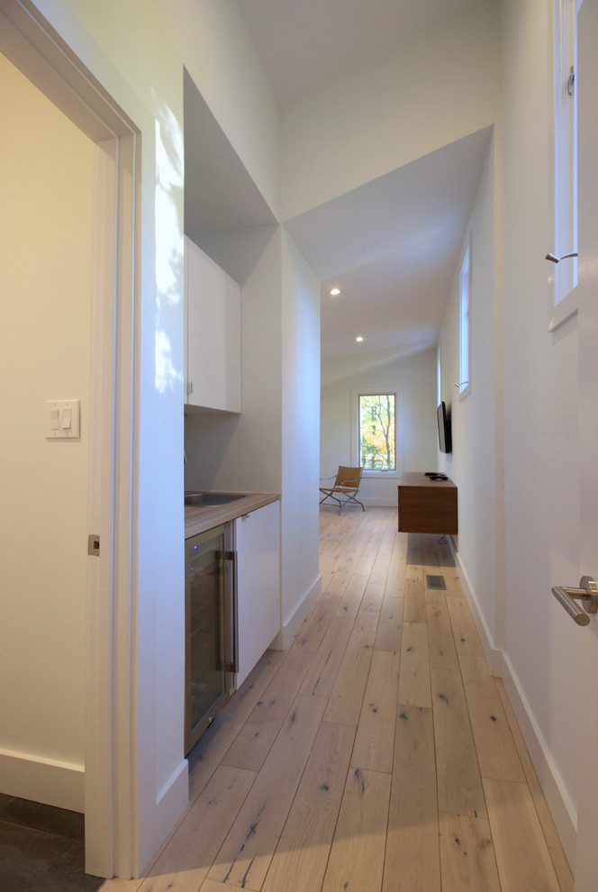 Imagen de recibidores y pasillos modernos de tamaño medio con paredes blancas, suelo de madera clara y suelo blanco