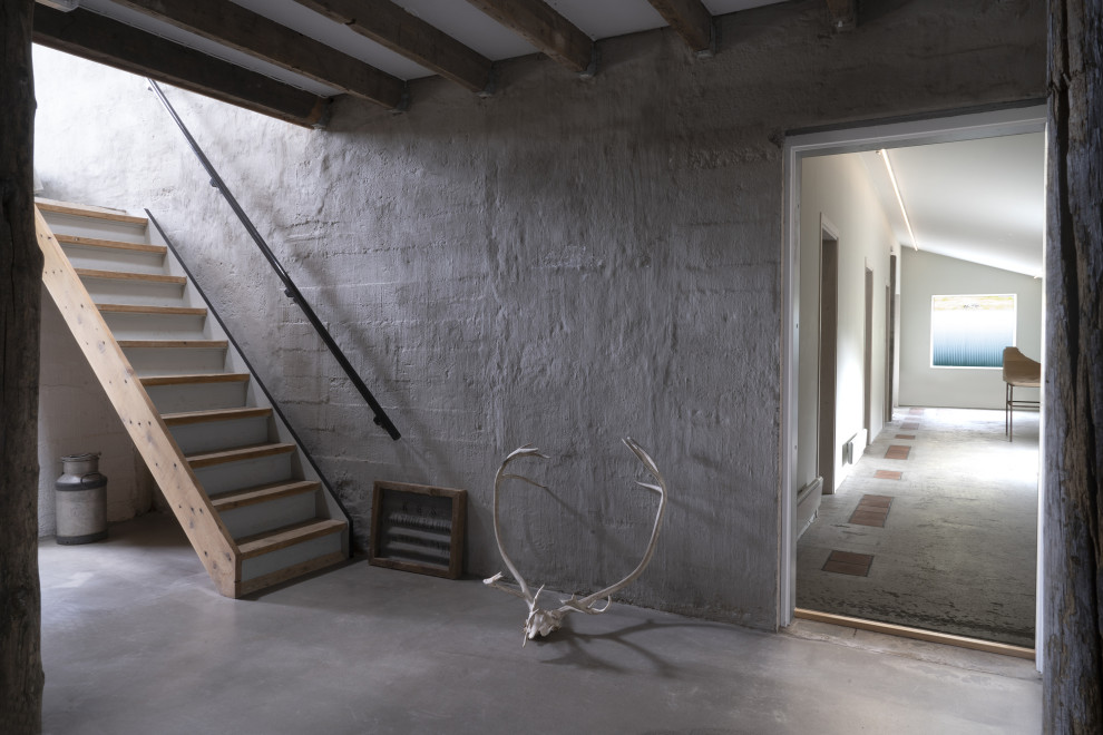 На фото: большой коридор в скандинавском стиле с серыми стенами, бетонным полом и серым полом с