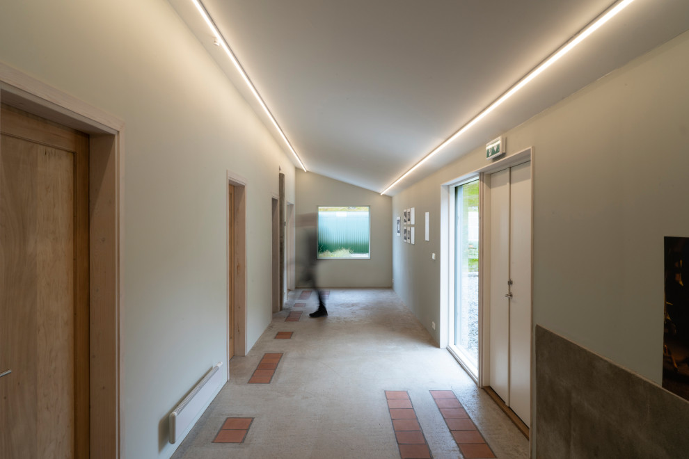 На фото: большой коридор в скандинавском стиле с серыми стенами, бетонным полом и серым полом