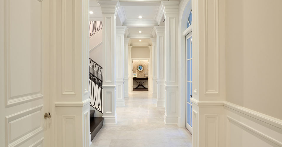 Aménagement d'un grand couloir classique avec un mur blanc et un sol en marbre.