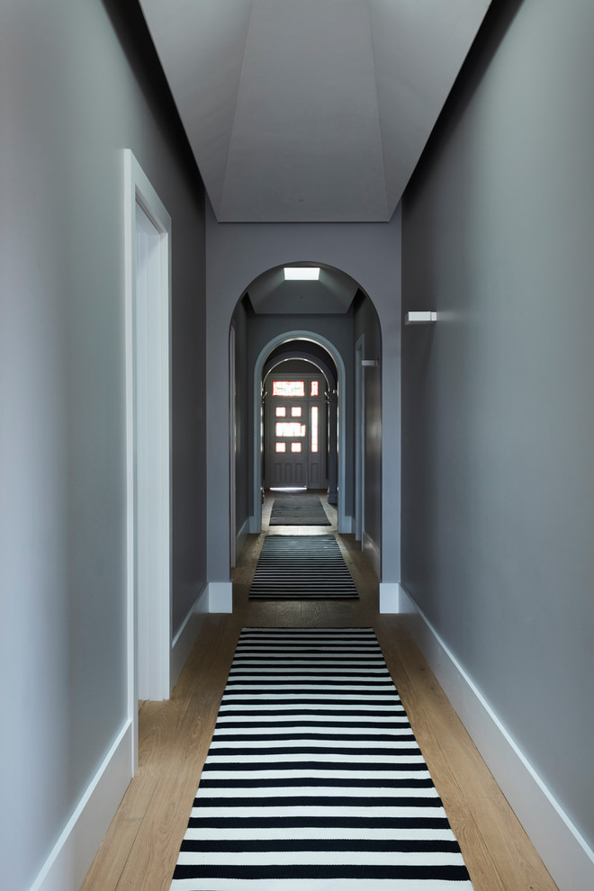 Exemple d'un couloir chic de taille moyenne avec un mur gris, un sol en bois brun et un sol marron.
