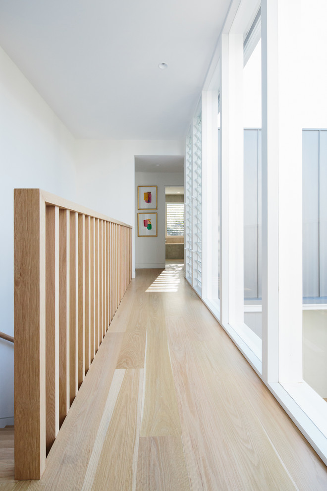 Inspiration for a mid-sized contemporary light wood floor hallway remodel in Other with white walls