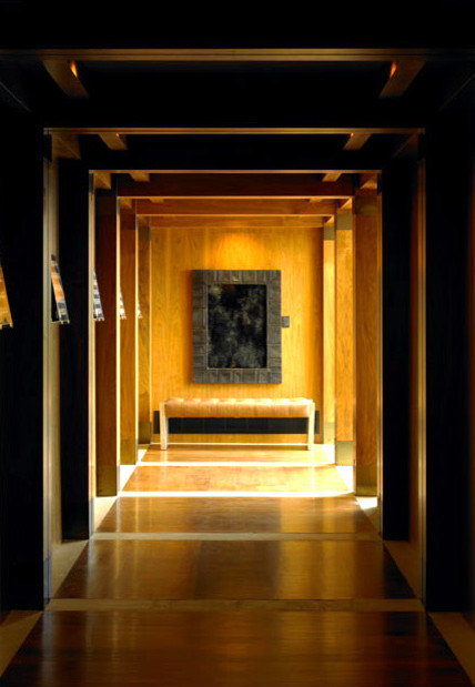 Cette image montre un grand couloir design avec un mur marron et un sol en bois brun.