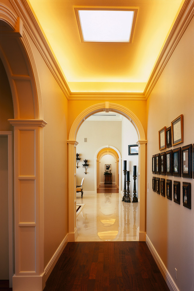 Пример оригинального дизайна: огромный коридор в средиземноморском стиле с бежевыми стенами, темным паркетным полом, коричневым полом и сводчатым потолком