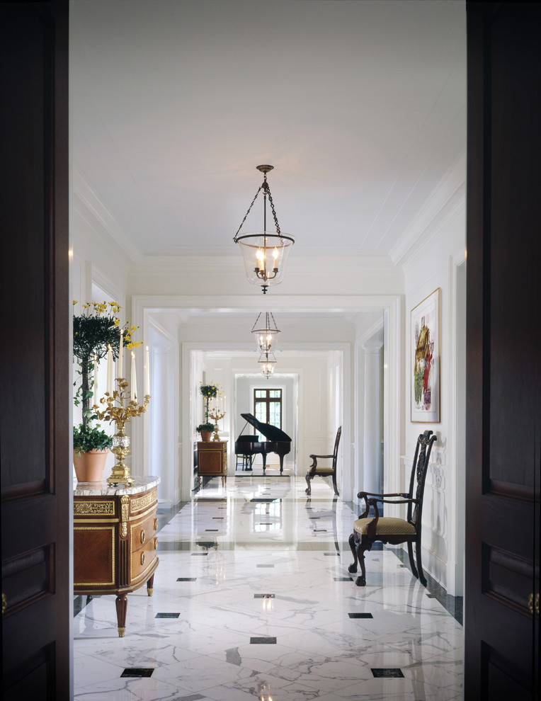На фото: большой коридор в классическом стиле с белыми стенами и мраморным полом с