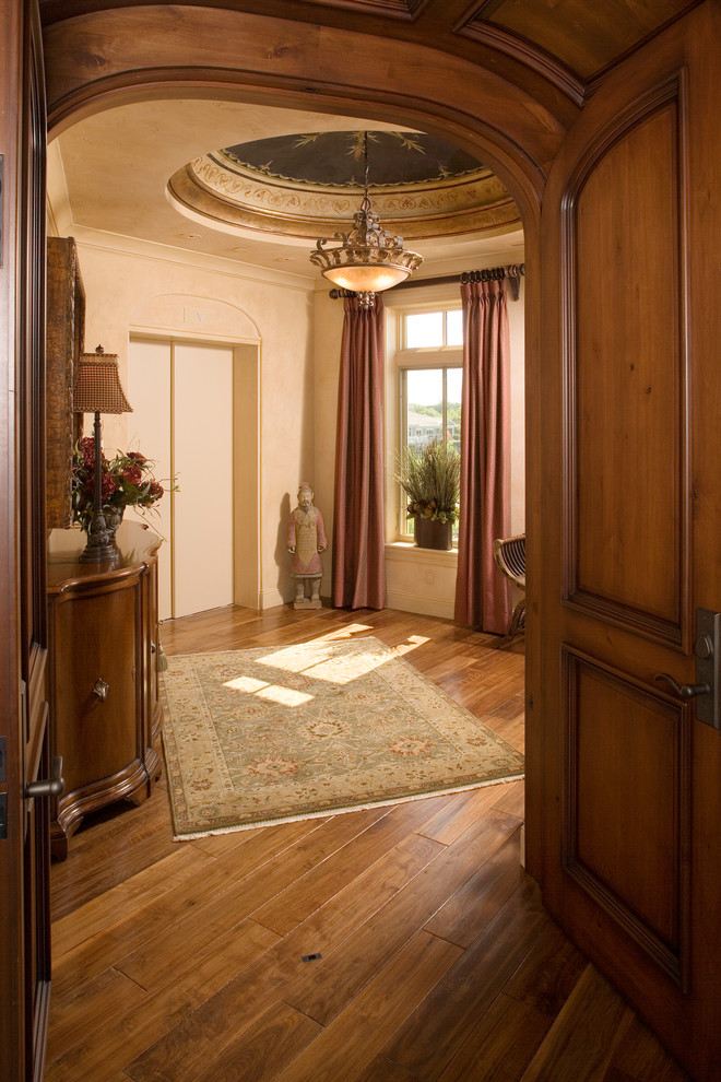 Esempio di un ingresso o corridoio mediterraneo di medie dimensioni con pareti beige e pavimento in legno massello medio
