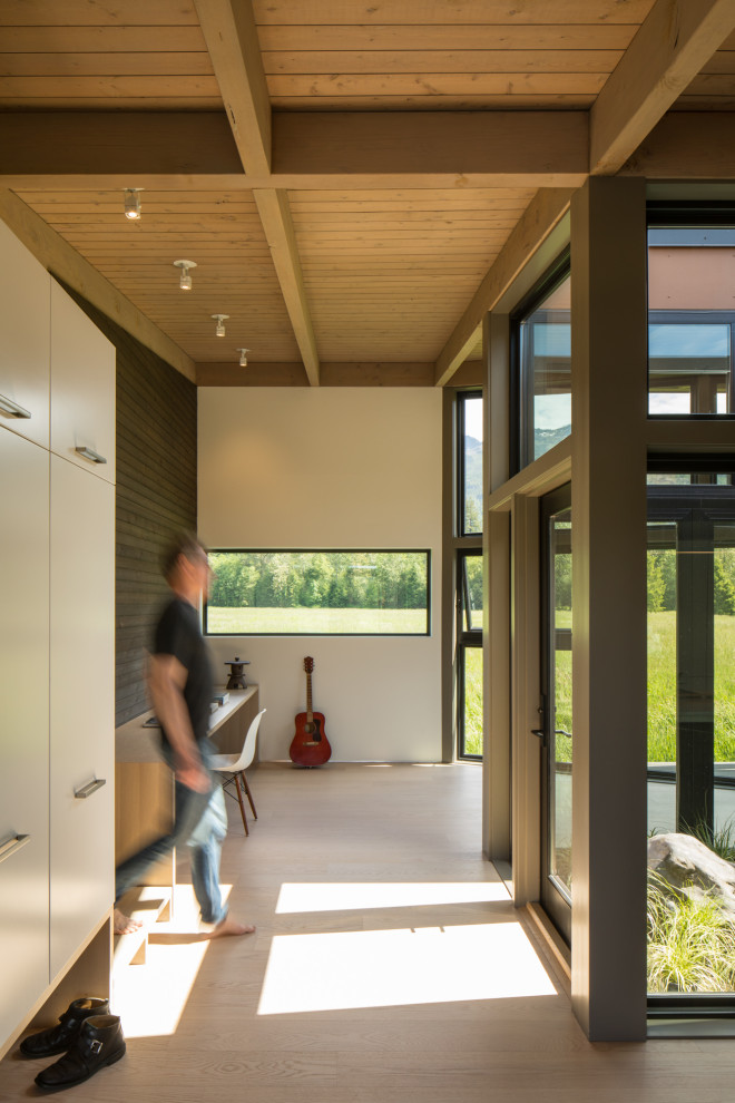 Diseño de recibidores y pasillos modernos con paredes blancas, suelo de madera clara y vigas vistas
