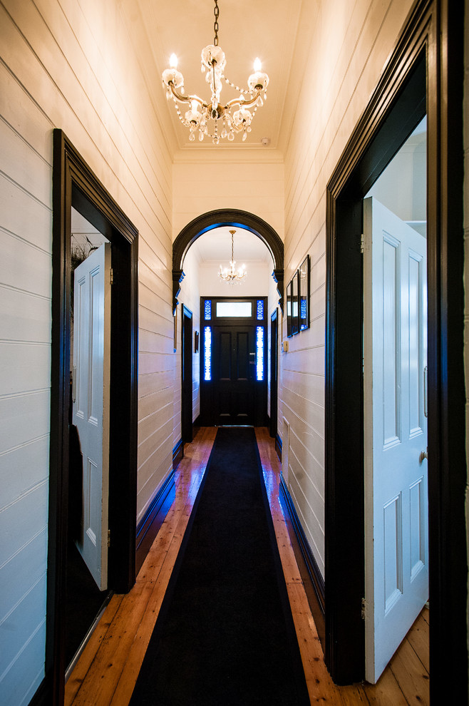 Inspiration pour un couloir bohème de taille moyenne avec un mur blanc et un sol en bois brun.