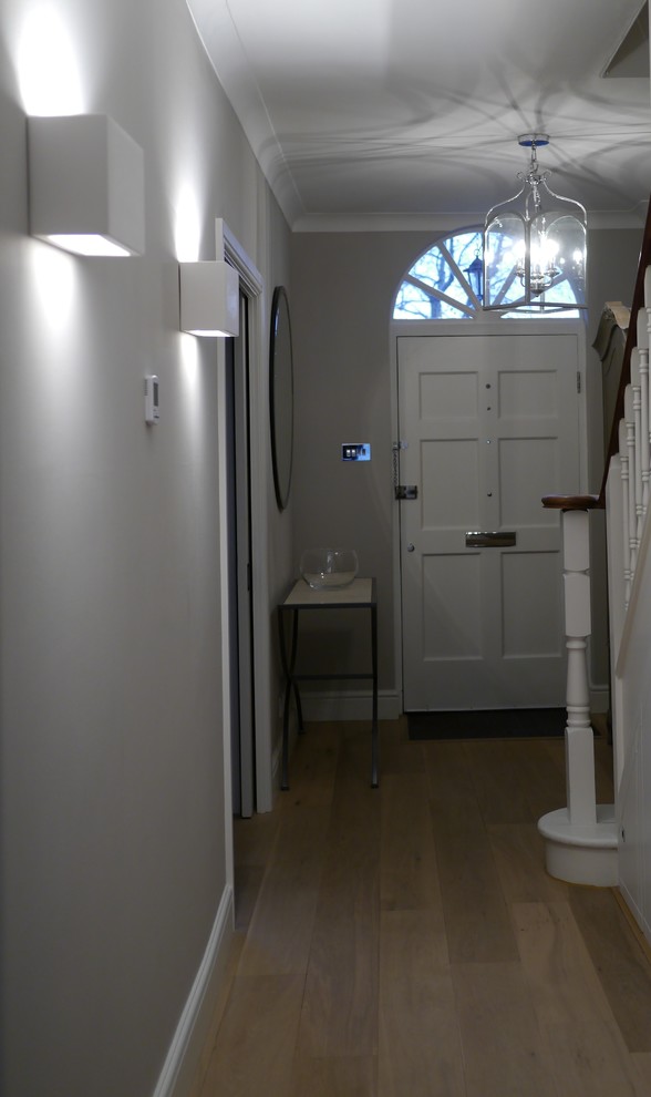 Immagine di un ingresso o corridoio minimalista di medie dimensioni con pareti grigie e parquet chiaro