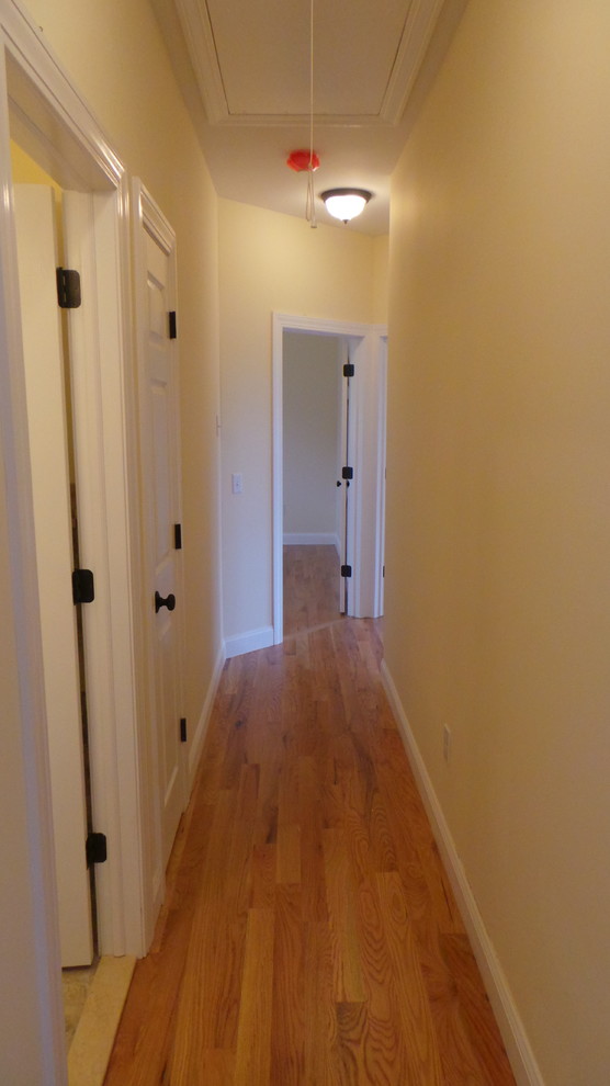 Inspiration pour un petit couloir design avec un mur beige et un sol en bois brun.