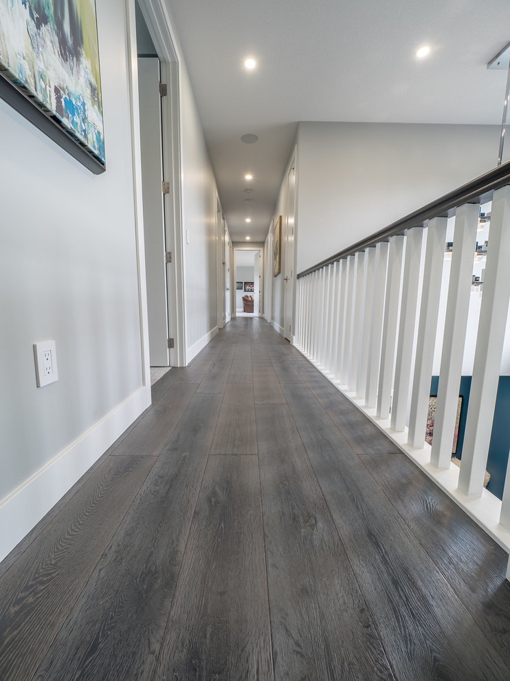 Cette photo montre un grand couloir moderne avec un mur gris, un sol en bois brun et un sol gris.