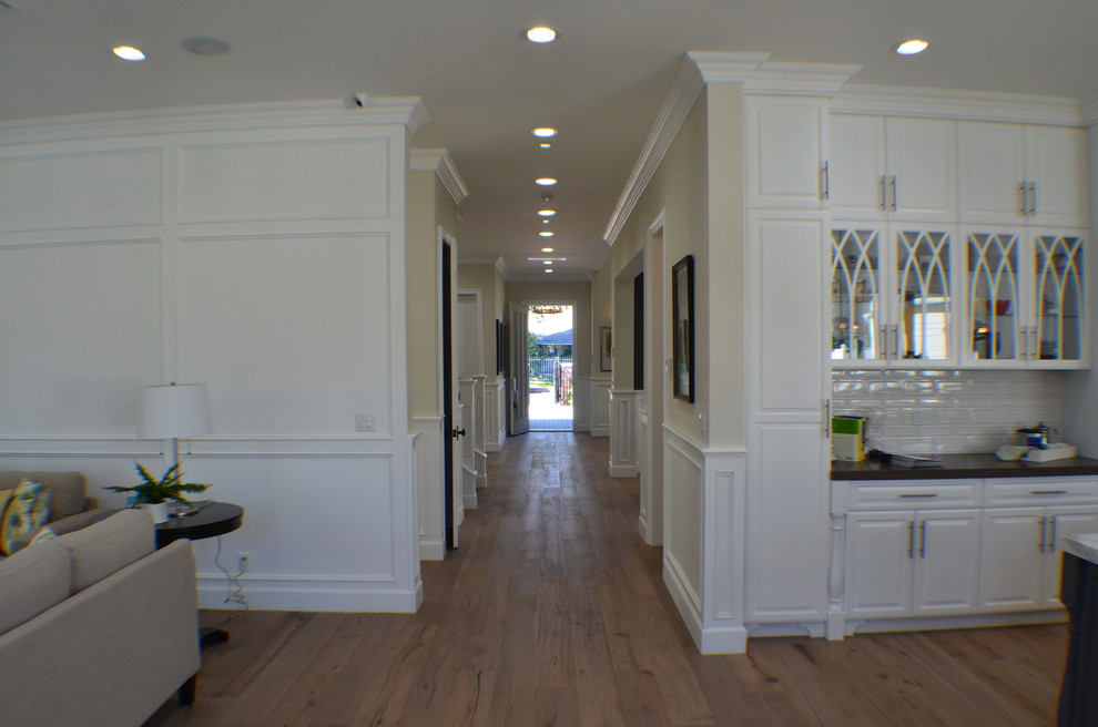 На фото: коридор среднего размера в стиле неоклассика (современная классика) с бежевыми стенами, светлым паркетным полом и коричневым полом с