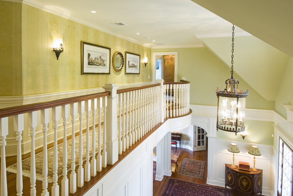 Imagen de recibidores y pasillos clásicos con paredes verdes, suelo de madera en tonos medios y iluminación