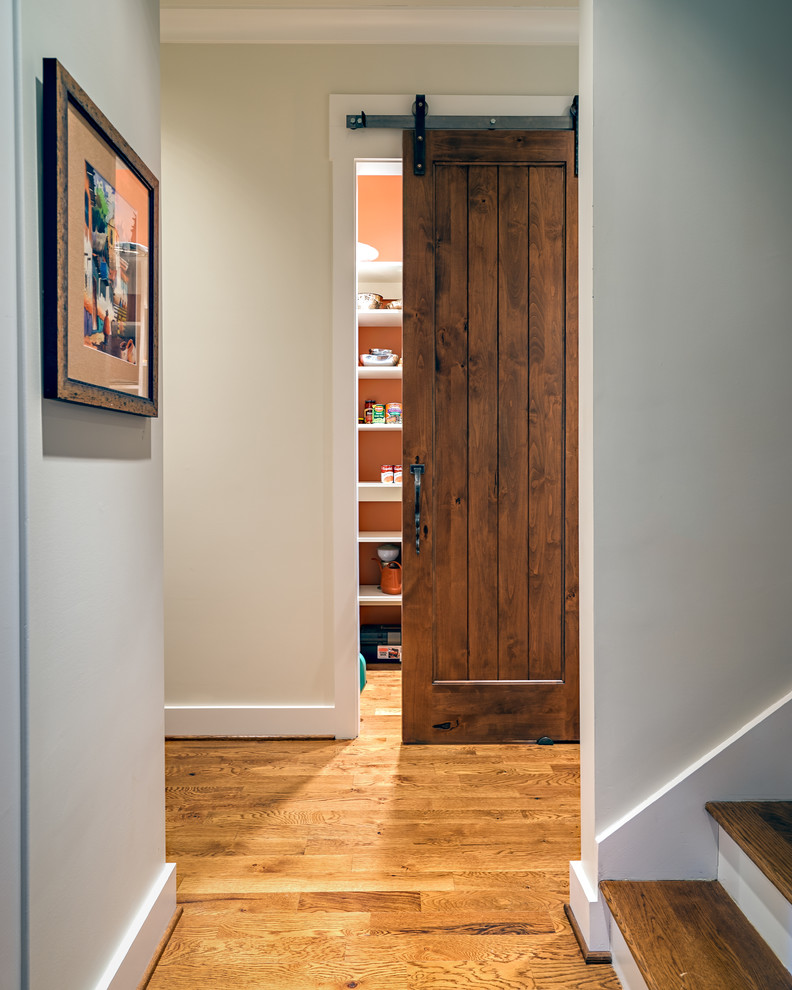 Cette image montre un petit couloir design avec un mur blanc et un sol en bois brun.