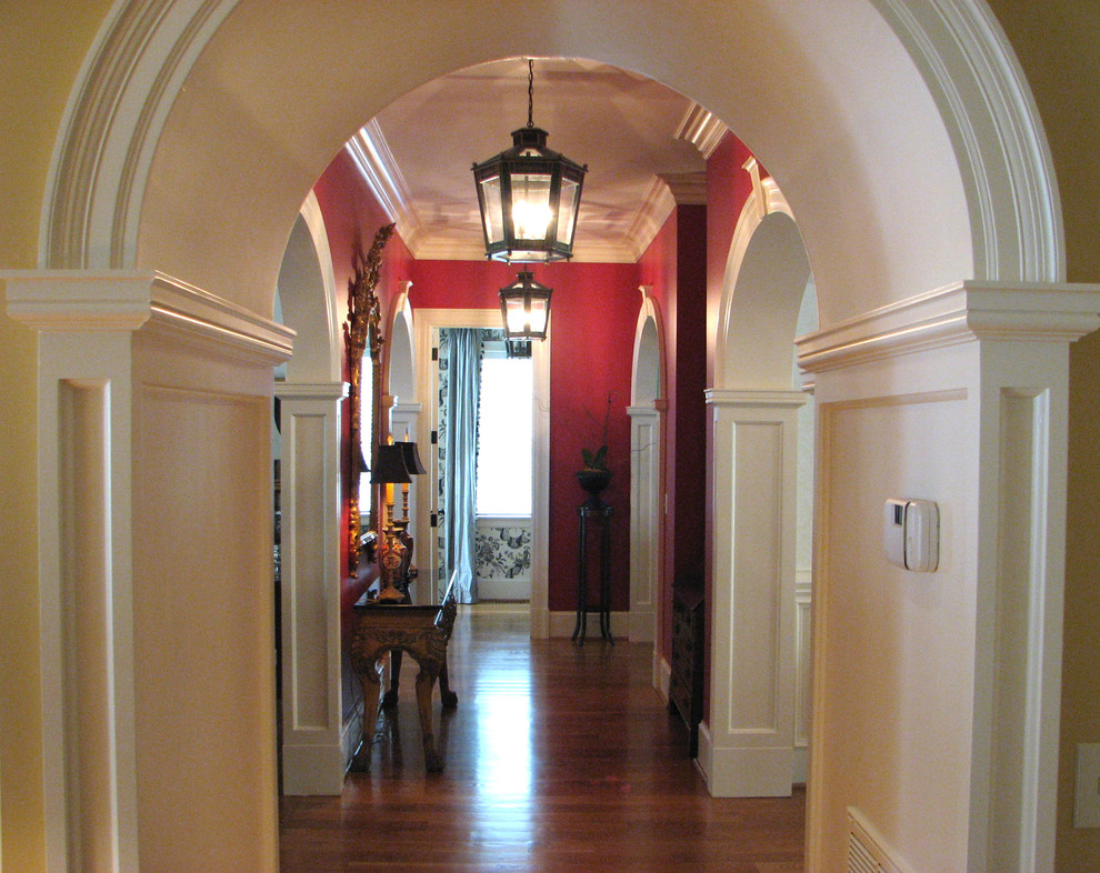 Diseño de recibidores y pasillos tradicionales de tamaño medio con paredes rojas, suelo de madera en tonos medios y iluminación