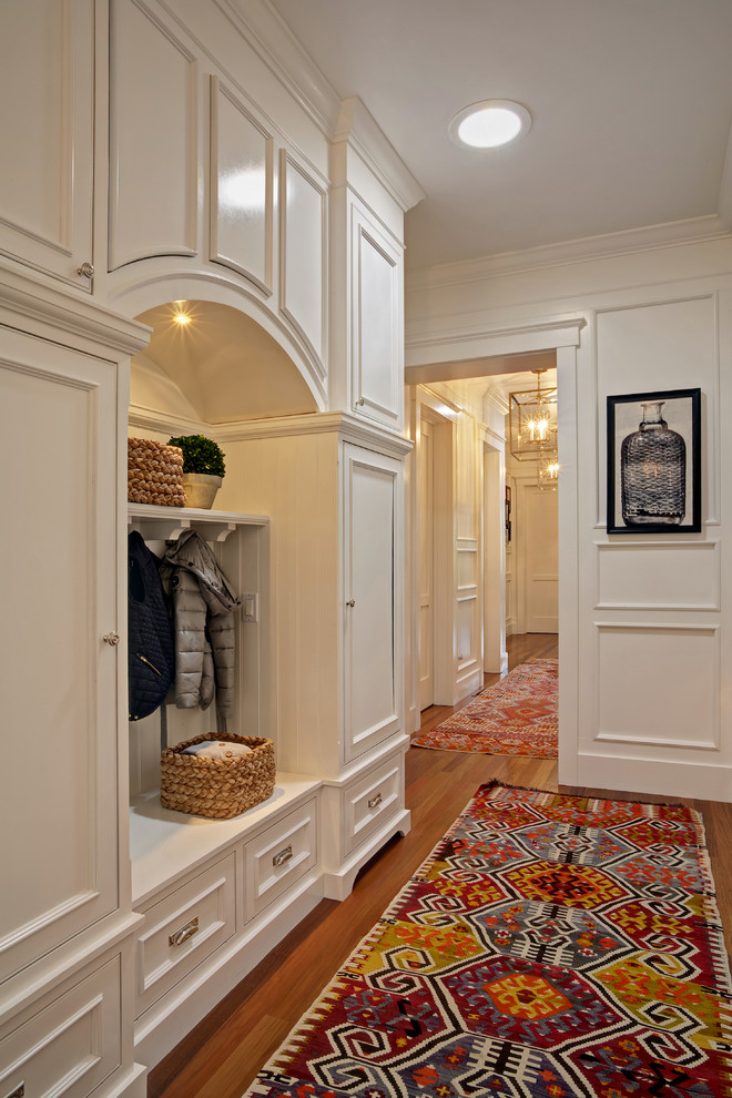 Inspiration pour un couloir traditionnel de taille moyenne avec un mur blanc et un sol en bois brun.