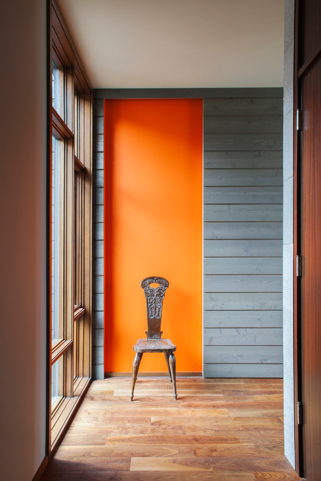 Diseño de recibidores y pasillos actuales con parades naranjas y suelo de madera en tonos medios