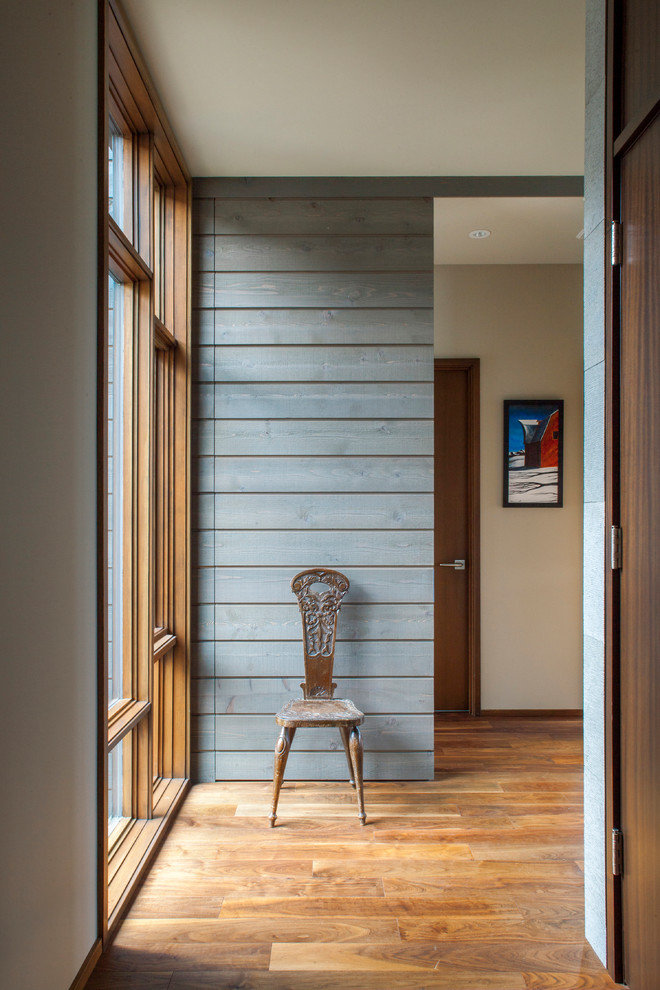 Réalisation d'un couloir design avec un mur gris et un sol en bois brun.
