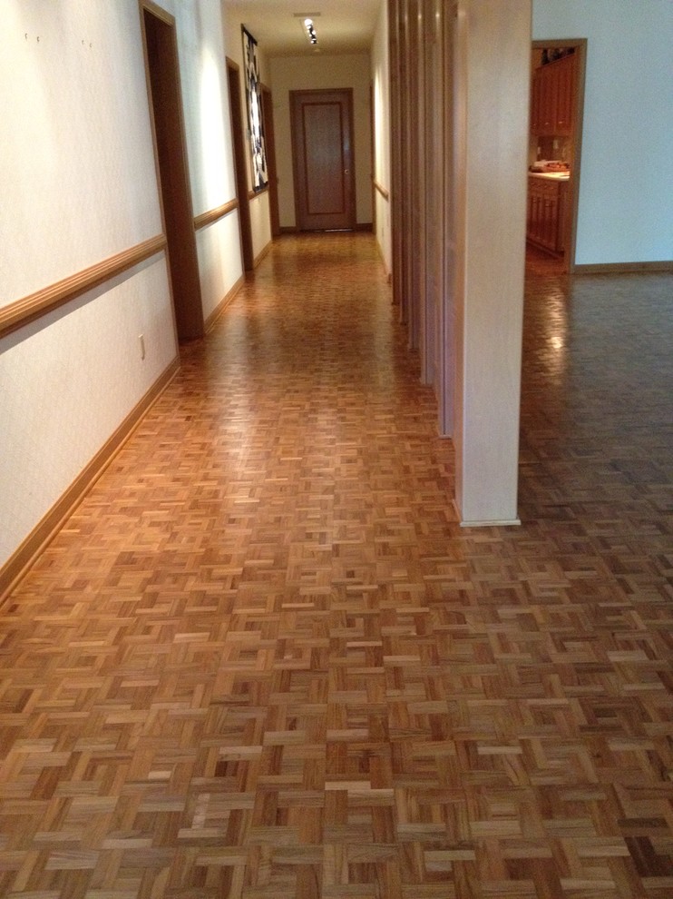 Réalisation d'un grand couloir vintage avec un mur blanc, un sol en bois brun et un sol marron.