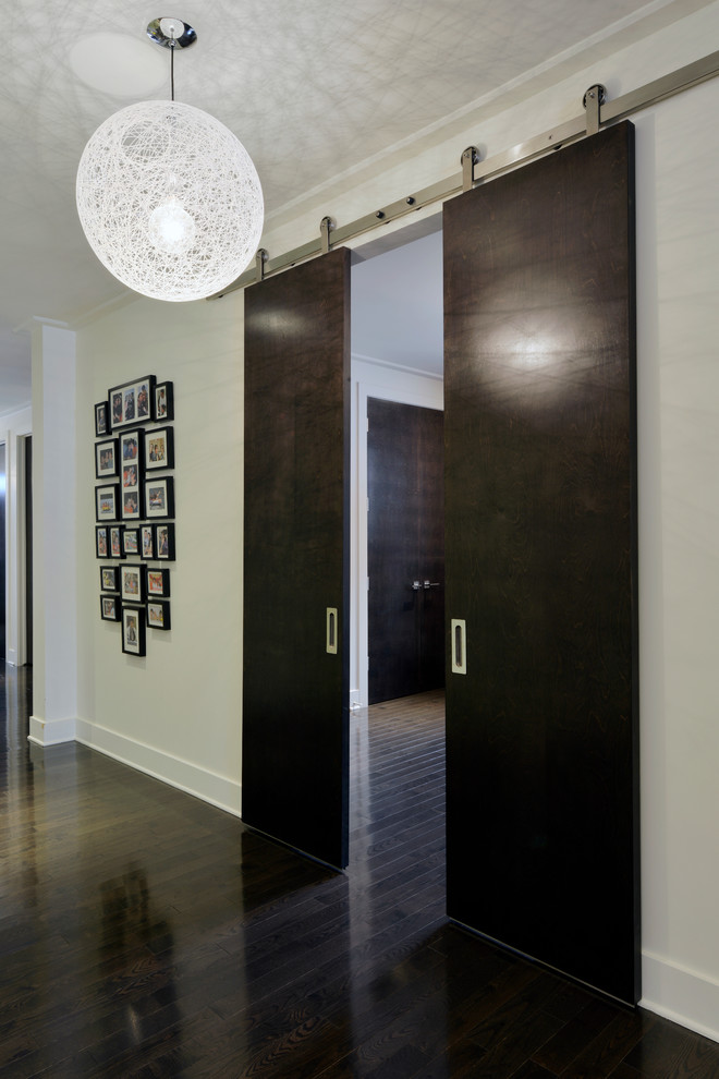 Aménagement d'un couloir contemporain avec un mur beige, parquet foncé et un sol noir.