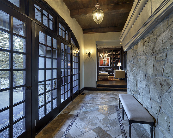 На фото: большой коридор: освещение в стиле рустика с серыми стенами и полом из травертина