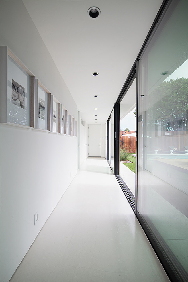Aménagement d'un couloir rétro de taille moyenne avec un mur blanc, sol en béton ciré et un sol beige.