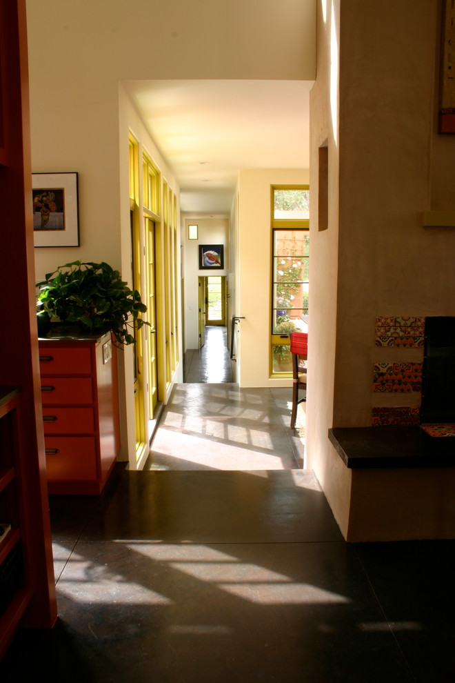Cette image montre un couloir bohème de taille moyenne avec un mur blanc, sol en béton ciré et un sol noir.