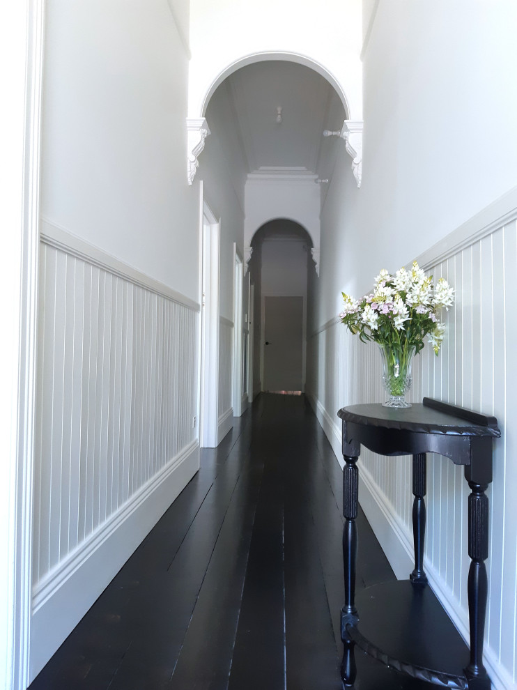 ジーロングにあるトラディショナルスタイルのおしゃれな廊下 (白い壁、濃色無垢フローリング、黒い床、羽目板の壁) の写真