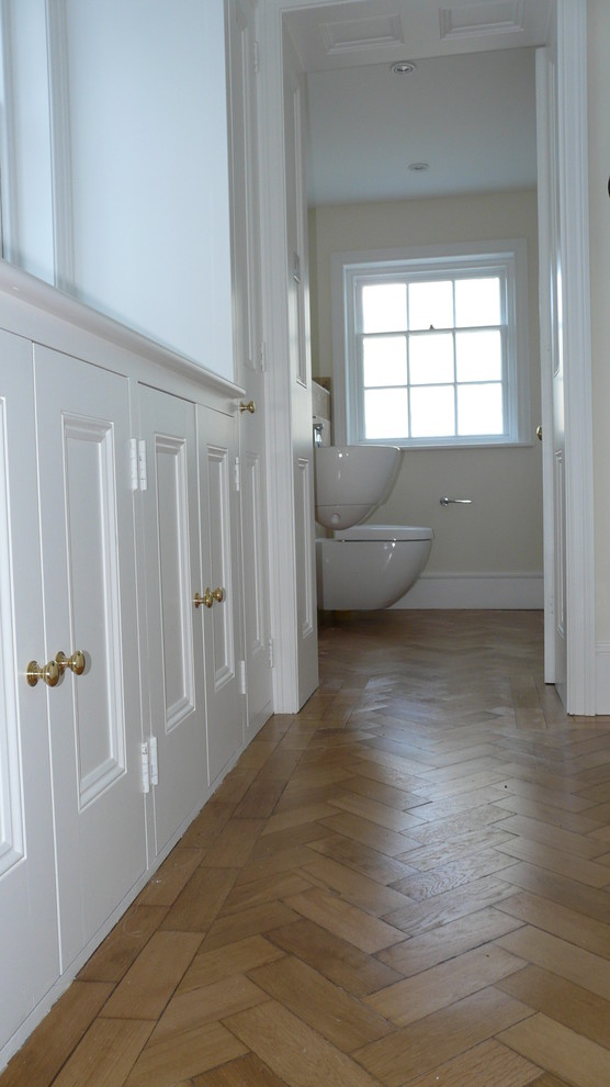 Cette photo montre un couloir chic de taille moyenne avec un mur blanc, parquet clair et un sol marron.