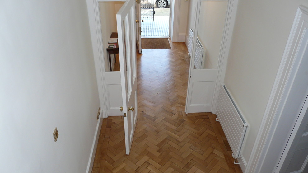 На фото: коридор среднего размера в классическом стиле с белыми стенами, светлым паркетным полом и коричневым полом