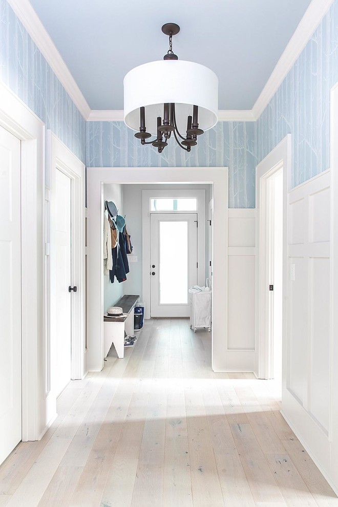 Exemple d'un couloir chic avec un mur bleu, parquet clair et un sol blanc.