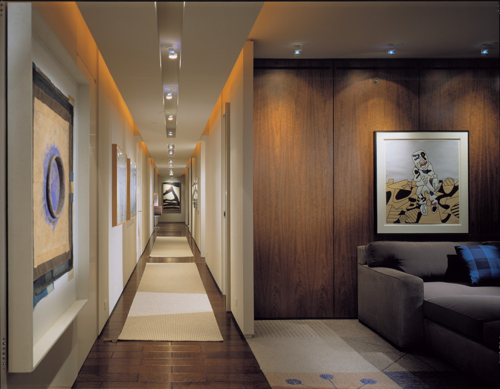 Idée de décoration pour un couloir design avec un mur blanc et parquet foncé.
