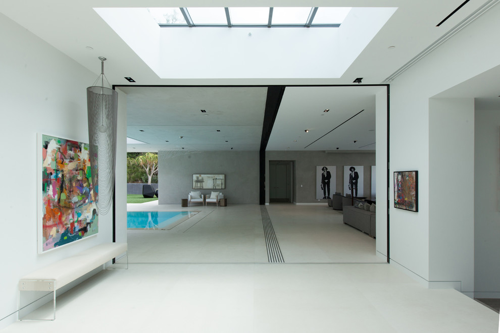 Стильный дизайн: огромный коридор в современном стиле с белыми стенами и полом из керамогранита - последний тренд