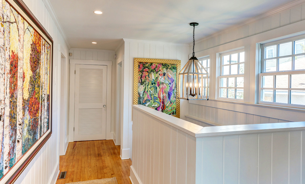 Inspiration for a large coastal light wood floor hallway remodel in Wilmington with white walls