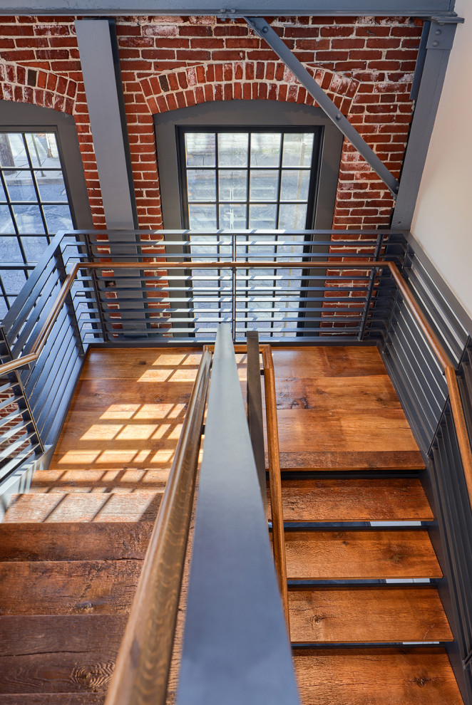Inspiration for a large industrial medium tone wood floor, brown floor, exposed beam and brick wall hallway remodel in Other with white walls