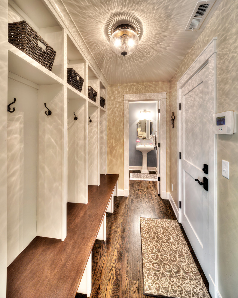 На фото: большой коридор: освещение в стиле неоклассика (современная классика) с коричневыми стенами и паркетным полом среднего тона с
