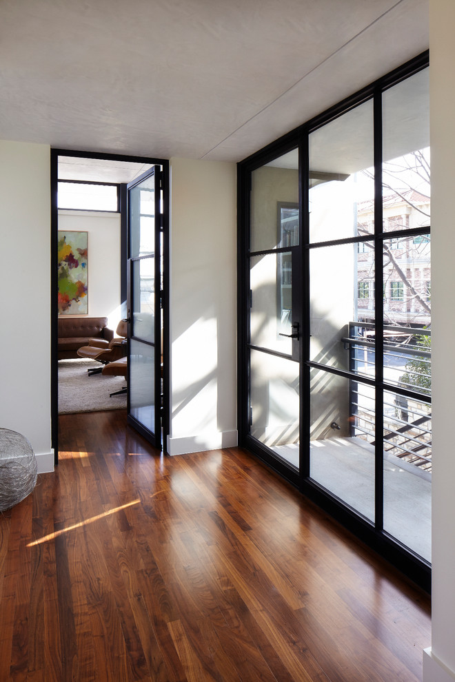 Idée de décoration pour un couloir minimaliste avec un mur blanc et un sol en bois brun.