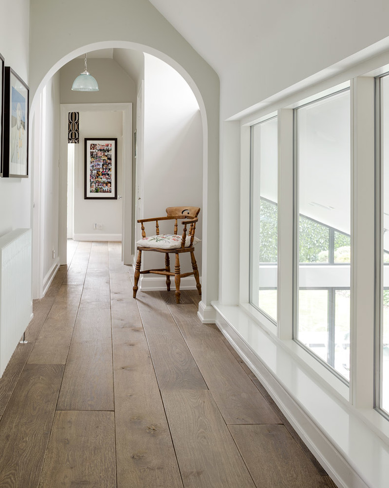 Hallway - transitional medium tone wood floor hallway idea in London with white walls