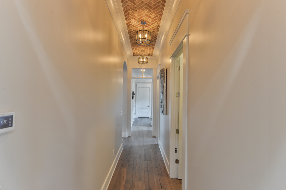 На фото: коридор среднего размера в стиле неоклассика (современная классика) с белыми стенами и темным паркетным полом