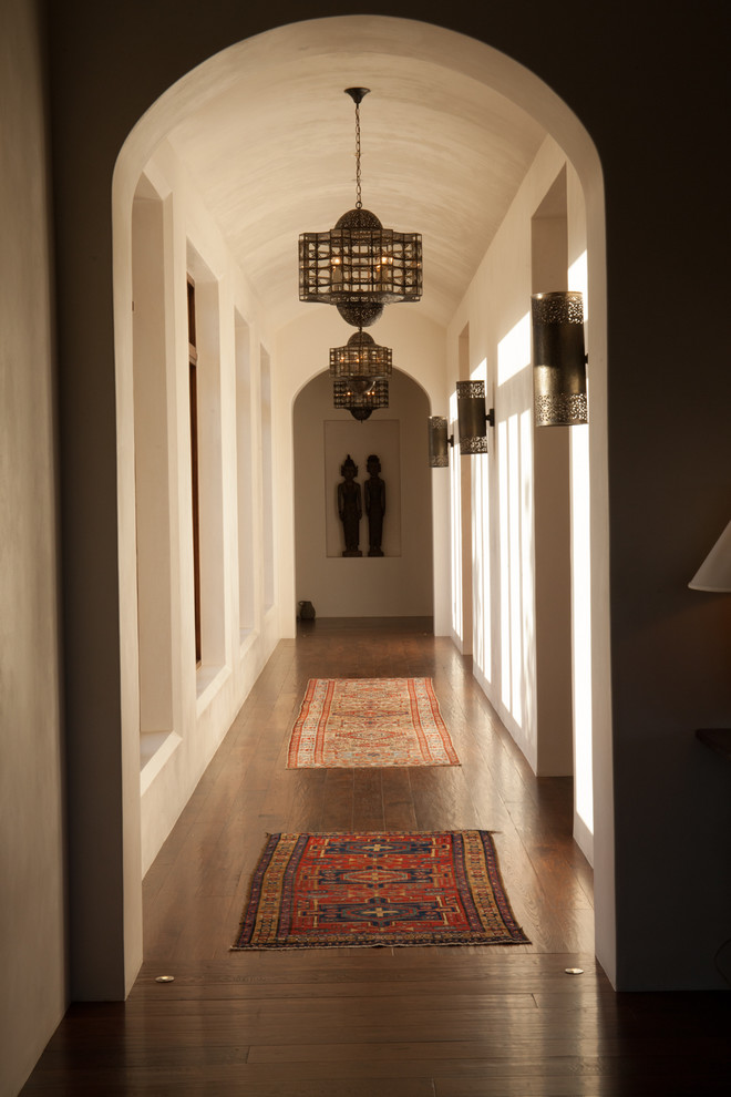 Aménagement d'un grand couloir classique avec un mur beige, parquet foncé et un sol marron.