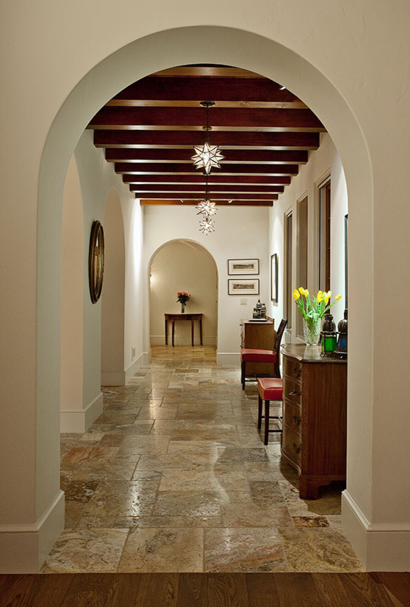 На фото: большой коридор в средиземноморском стиле с белыми стенами и полом из травертина
