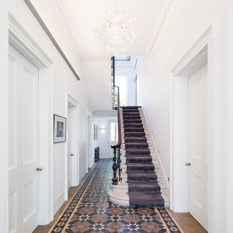 Idée de décoration pour un couloir tradition de taille moyenne avec un mur blanc, un sol en carrelage de céramique et un sol multicolore.