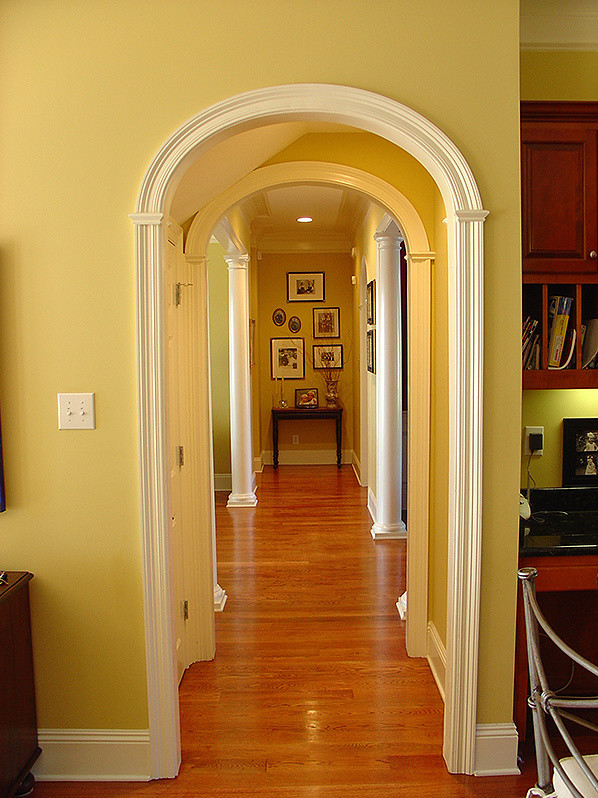 Exempel på en liten klassisk hall, med gula väggar, mellanmörkt trägolv och brunt golv