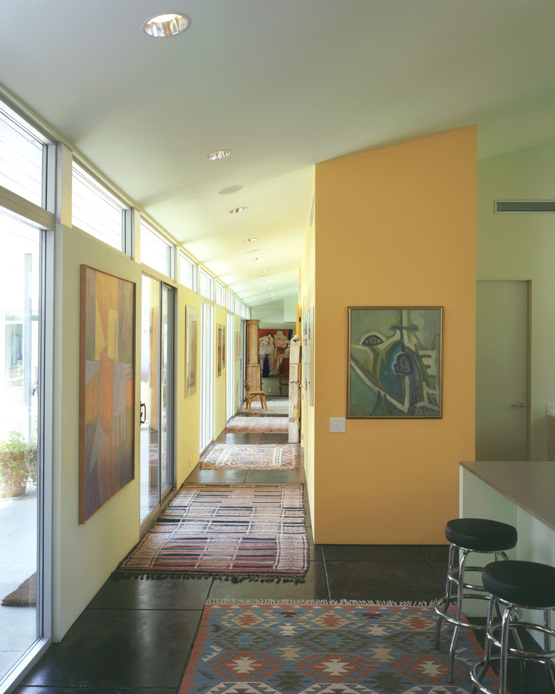 Cette image montre un couloir vintage avec un mur orange et sol en béton ciré.
