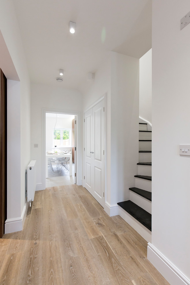 Esempio di un piccolo ingresso o corridoio minimal con pareti bianche, parquet chiaro e pavimento marrone